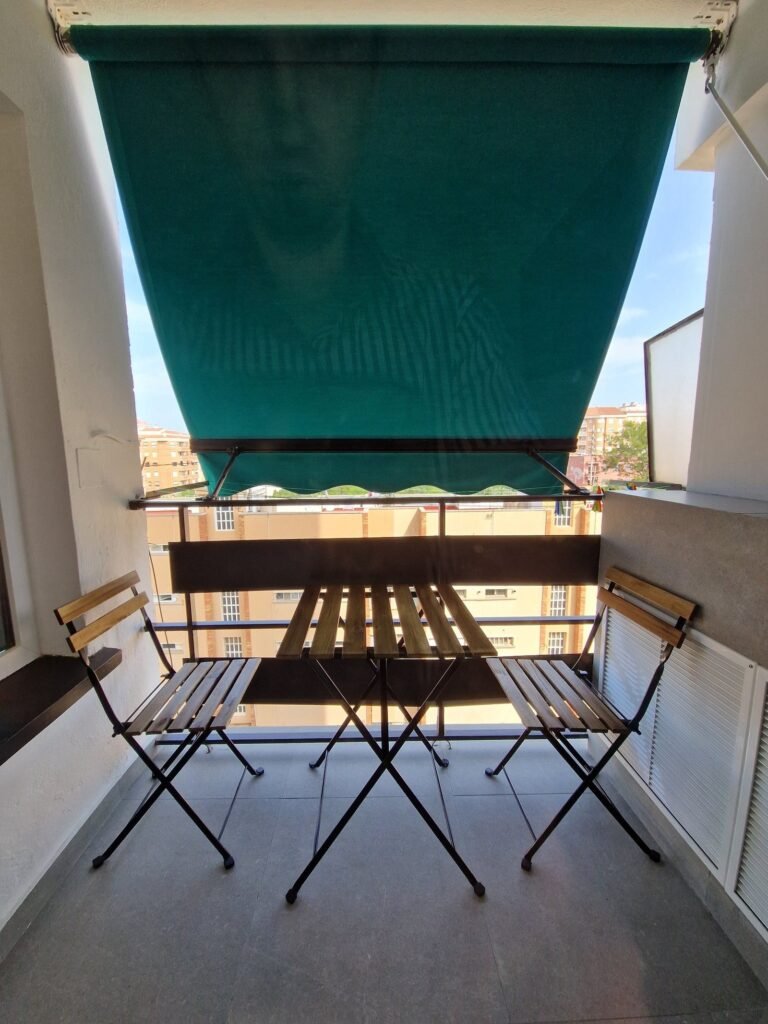 Balcón con toldo y mesa exterior