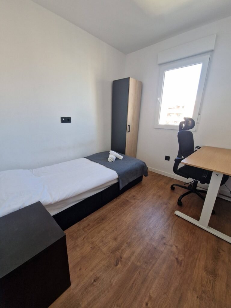 Dormitorio individual con escritorio y silla de oficina